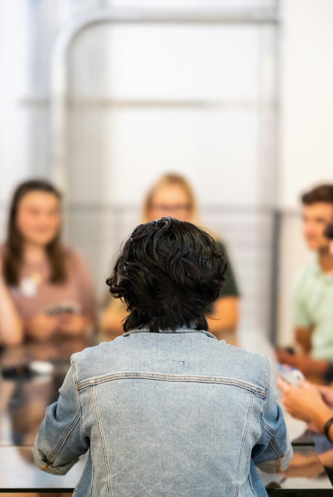pexels-photo-34516196-34516196 A group of young adults engaged in a lively discussion around a table indoors.